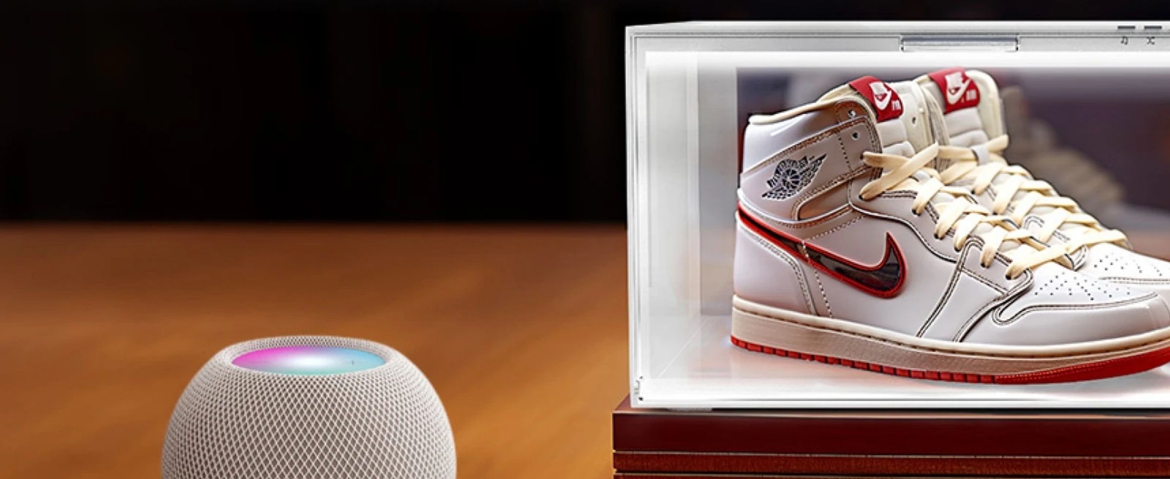 A luxury sneaker encased in a transparent display box with glowing light, next to a smart speaker on a wooden surface.